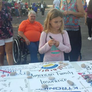 A young girl participating in a community event, engaging with a table of information from American Family Insurance.
