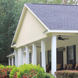 A house with a columned porch and landscaped garden.