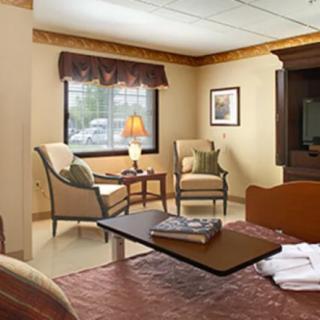 A cozy living room with two chairs, a small table with a lamp, and a window letting in natural light.