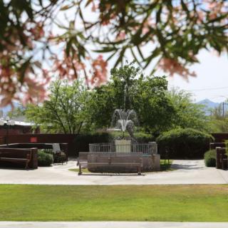A scenic view of a garden with a central fountain surrounded by trees.