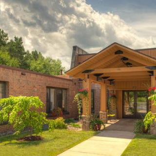 A charming brick building with a landscaped entrance under a partly cloudy sky.