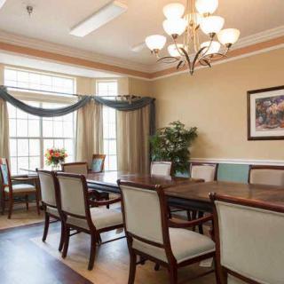 A well-furnished dining room with a large table and chairs, illuminated by an elegant chandelier.