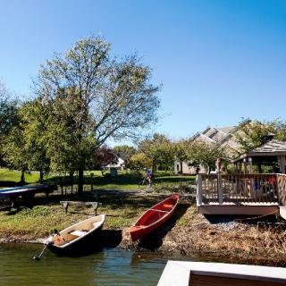 A scenic view of small boats docked on a tranquil lake near houses and lush greenery.