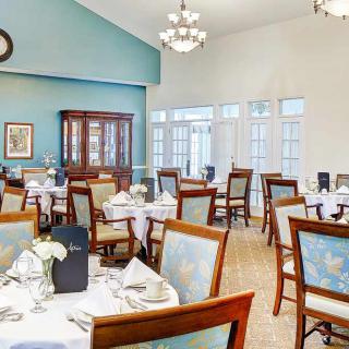 An elegant dining room with neatly arranged tables and chairs, adorned with chandeliers.