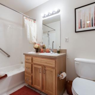 A clean and modern bathroom featuring a wooden vanity, mirror, and white fixtures.
