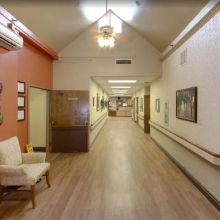 A long corridor in a nursing home with chairs and paintings on the walls.