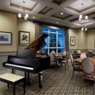 A cozy lounge room featuring a grand piano, elegant seating, and artistic decor.