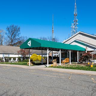A view of a building with a green awning and an antenna, surrounded by trees under a clear blue sky.