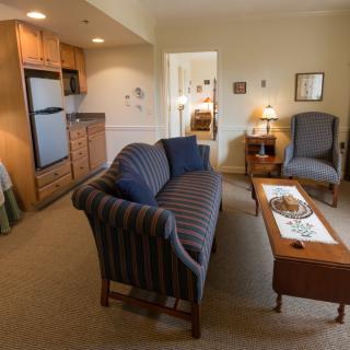 A cozy apartment living room with a sofa, coffee table, and kitchenette.