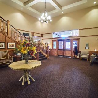 A spacious hotel lobby with a grand staircase and elegant wooden decor.