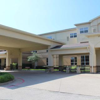 A large building with a covered entrance and driveway, photographed during the day.