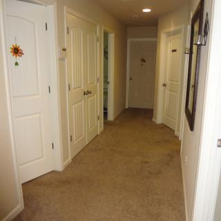 A carpeted residential hallway with multiple doors on both sides.