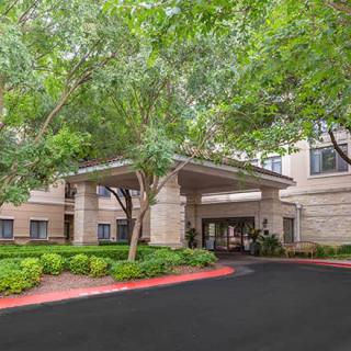 The entrance to a building surrounded by trees and landscaped greenery.