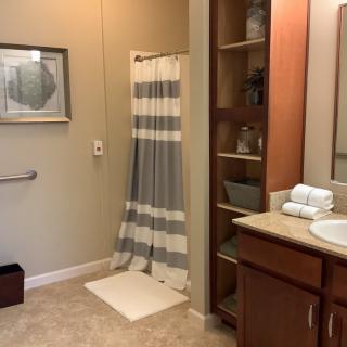 A well-organized bathroom featuring a striped shower curtain, sink with countertop, and storage shelves.