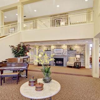 A spacious and elegantly decorated lobby featuring a piano, fireplace, and comfortable seating.