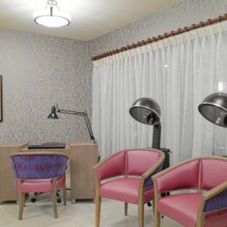 A cozy beauty salon interior with pink chairs and hair dryers.