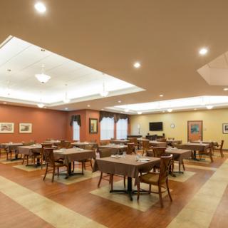 A spacious dining room with neatly arranged tables and chairs, featuring warm lighting and inviting decor.