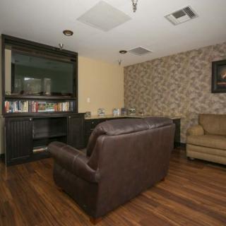A cozy living room with a brown leather sofa, bookshelf, and patterned wallpaper.