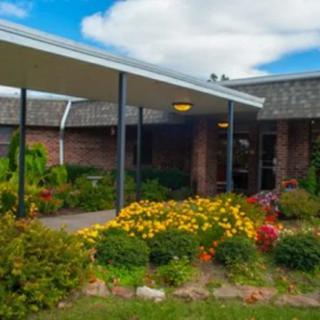 A building with a covered entrance surrounded by a vibrant garden and lush landscaping.