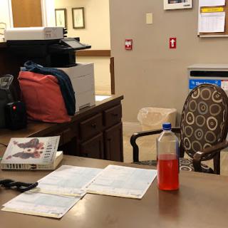A workspace with a desk, some books, a drink, and an empty chair.