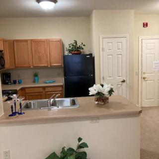A cozy kitchen with wooden cabinets, a black refrigerator, and a countertop adorned with flowers.