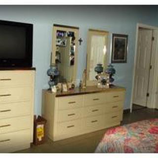 A bedroom with a dresser, mirrors, and a television.