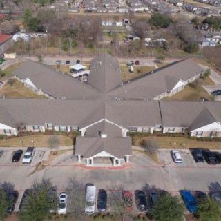 Aerial view of a large building with a parking lot in a suburban area.