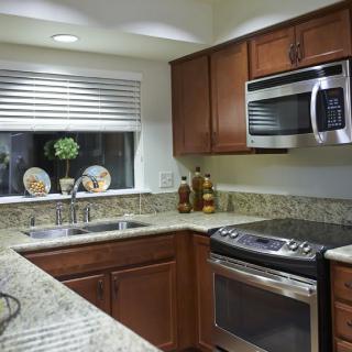 A modern kitchen featuring granite countertops, stainless steel appliances, and wooden cabinets.
