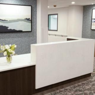 A modern office reception area with a sleek desk, artwork on the walls, and fresh flowers.