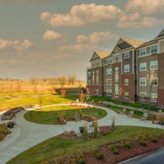 A picturesque view of a residential building surrounded by landscaped gardens and pathways at sunset.