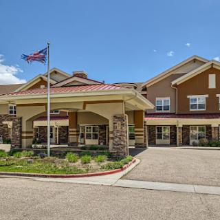A welcoming hotel entrance with an American flag waving in front under a clear blue sky.