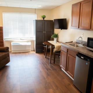 A modern studio apartment with a kitchenette, dining table, and comfortable seating area.