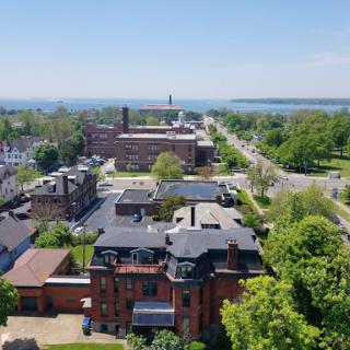Aerial view of a scenic city landscape with lush greenery and a waterfront in the background.