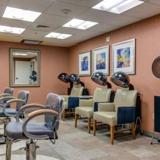 A cozy hair salon interior featuring chairs, hair dryers, mirrors, and wall art.