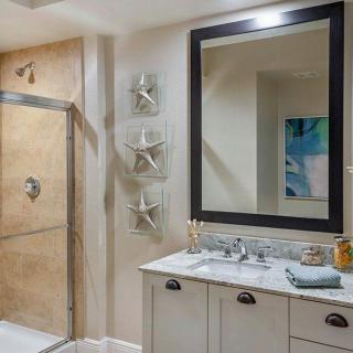A modern bathroom featuring a large mirror, vanity with sink, and glass-enclosed shower.