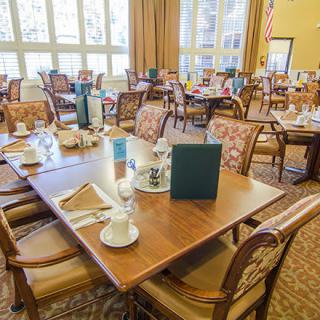 A cozy dining room with multiple tables and chairs, neatly set with menus and tableware.