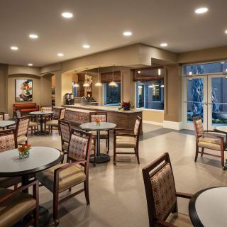 A modern dining area with neatly arranged tables and chairs, illuminated by soft overhead lighting.