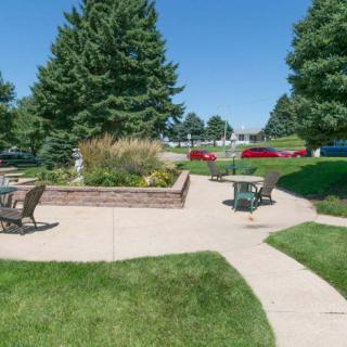 A serene outdoor area with patio furniture, surrounded by trees and a well-maintained lawn.