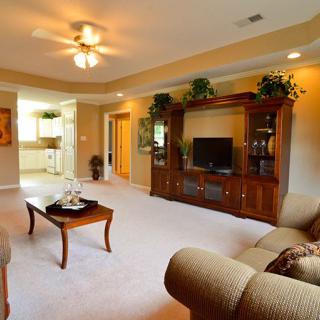 A cozy living room with a wooden entertainment center, comfortable seating, and elegant decor.
