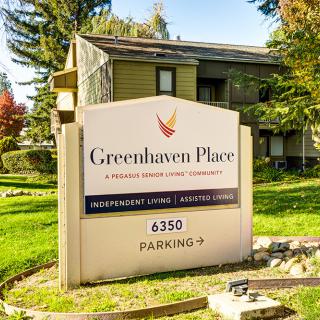 A sign for Greenhaven Place, a senior living community, located in a landscaped outdoor setting.
