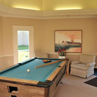 A cozy billiard room featuring a pool table, comfortable seating, and wall art.