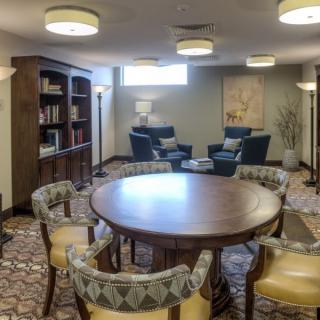 A cozy lounge area featuring a round table with chairs, bookshelves, and comfortable seating.