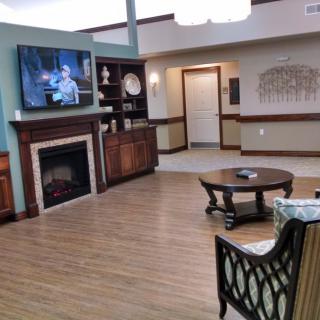 A cozy living room with a fireplace and television, featuring comfortable seating and a wooden coffee table.