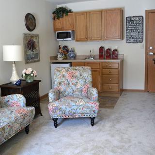 A cozy living area featuring floral armchairs and a small kitchenette.