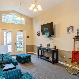 A cozy living room with a wall-mounted TV, comfortable seating, and a popcorn machine.