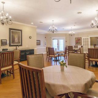 A well-lit dining room with wooden furniture and elegant chandeliers.