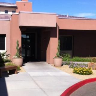 A modern building entrance with desert landscaping and potted plants.