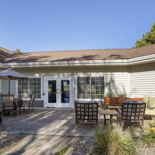 A sunny patio with outdoor furniture and a view of the house's back entrance.