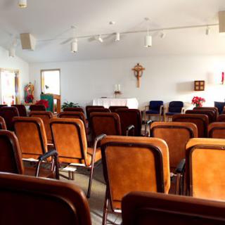 An empty church interior with rows of chairs facing the altar.