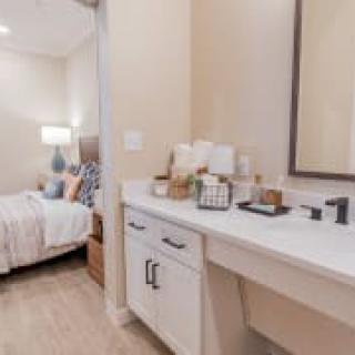 A cozy bedroom with a connected vanity area, featuring soft lighting and elegant decor.
